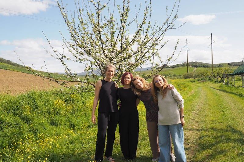 Three team members under a blossoming tree in the Tuscan countryside
