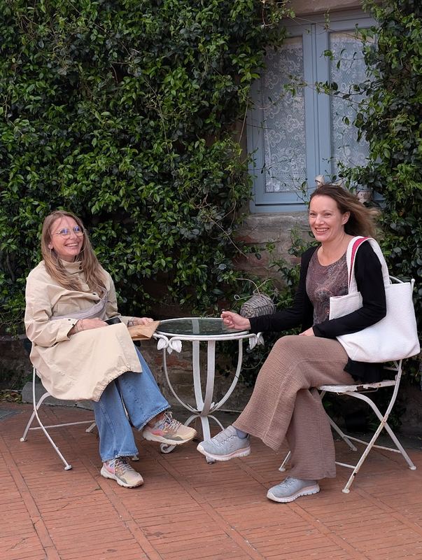 Two colleagues talking at a small table by a brick wall