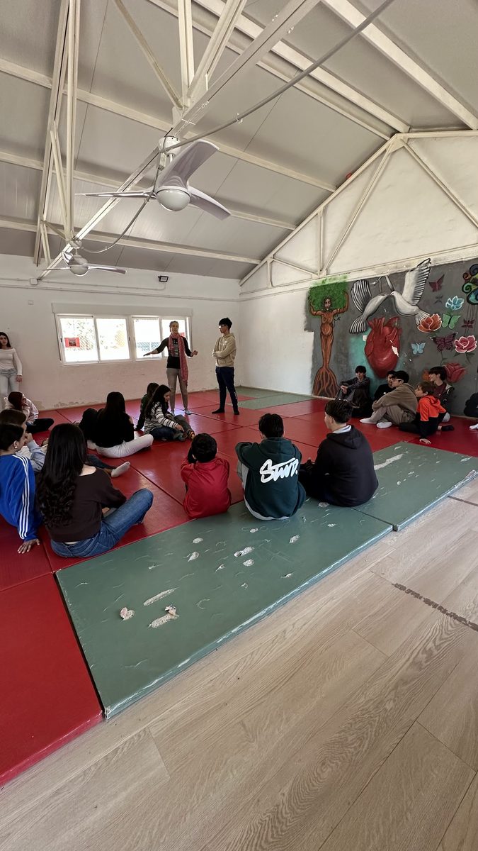 Young people sitting on mats during a piloting session at a school
